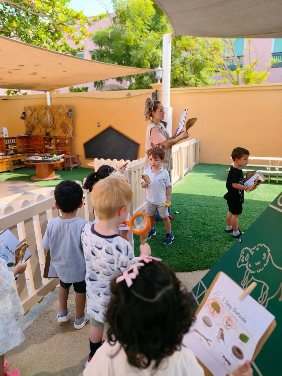 Children in the nursery garden holding picture checklists during a nature hunt